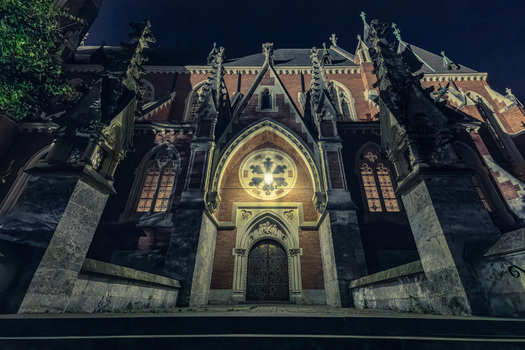 beleuchtetes Seitenportal einer neogotischen Kirche
