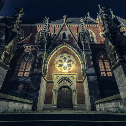 beleuchtetes Seitenportal einer neogotischen Kirche